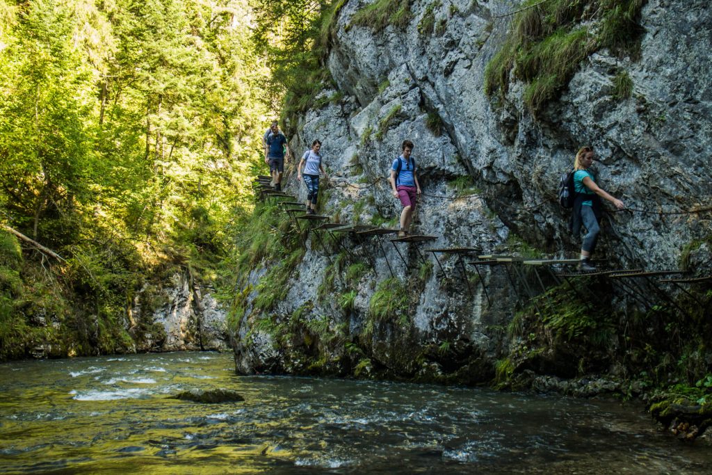 hikers walking on iron ledges above river hornad in slovak paradise